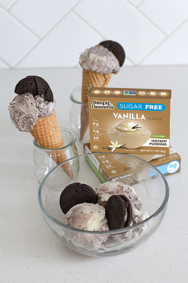 Close-up of cookies and cream ice cream scoops with chocolate cookies in a glass bowl and cones behind