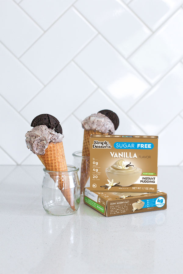 Cookies & Cream Pudding Ice Cream Featured ImageCookies & Cream Pudding Ice Cream Front View Vanilla pudding mix box with two ice cream cones in jars behind it on a white kitchen counter