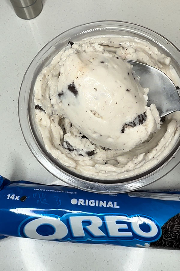 A scoop of Oreo ice cream being lifted from the Creami container, showing the smooth texture and embedded cookie bits