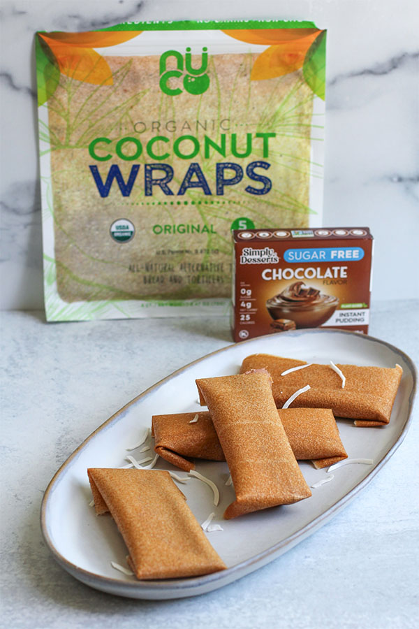 Chocolate Coconut Ice Cream Wraps with Ingredients Plate of chocolate coconut ice cream wraps in front of Nuco Coconut Wraps and Simply Dessert Chocolate Pudding packaging